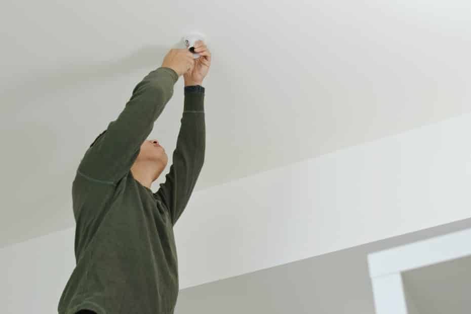 Man install the lamp on ceiling at home