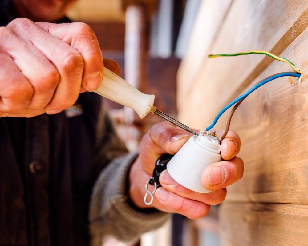 Hands of unrecognizable electrician working with screwdriver